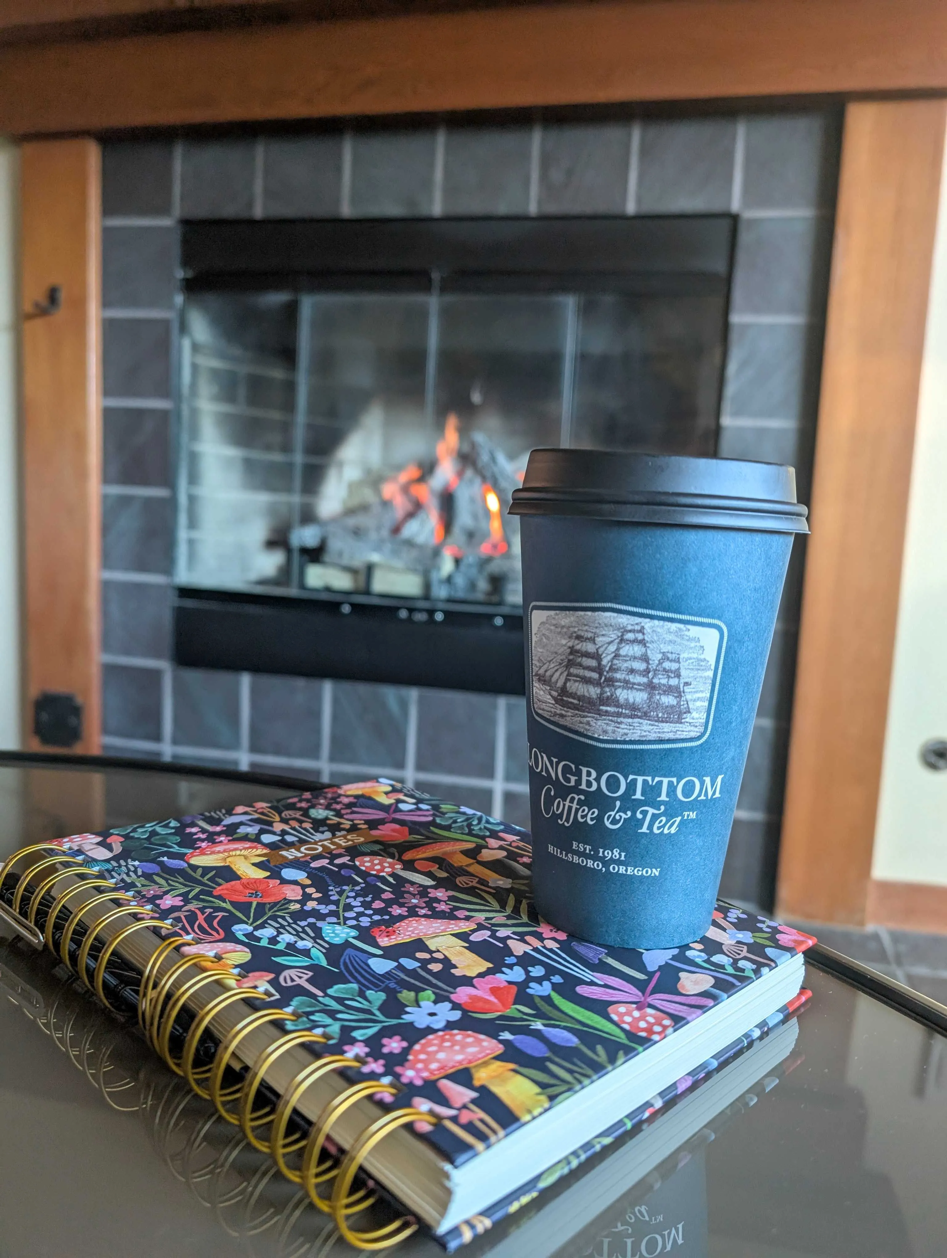 A coffee cup from Longbottom coffee and tea in front of a fireplace