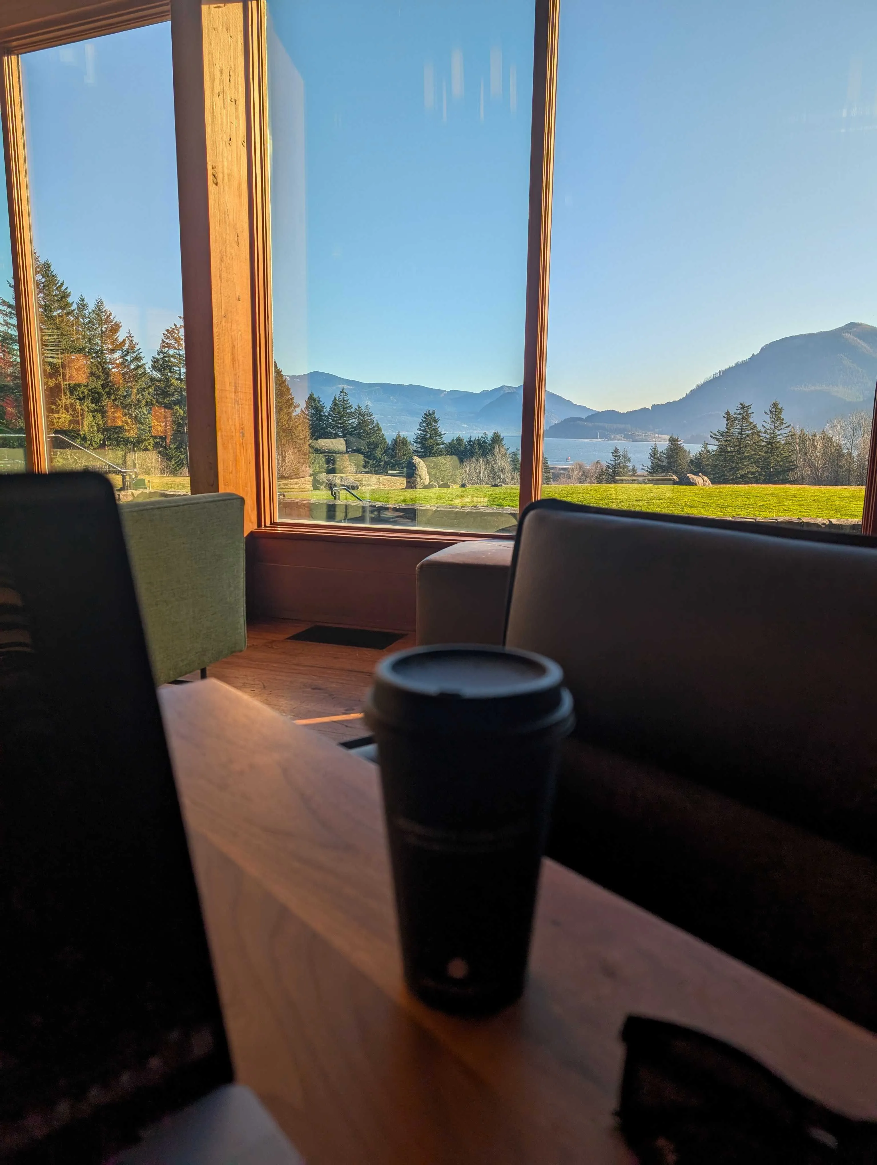 A coffee cup in front of a window with a view of the Columbia River Gorge in the background